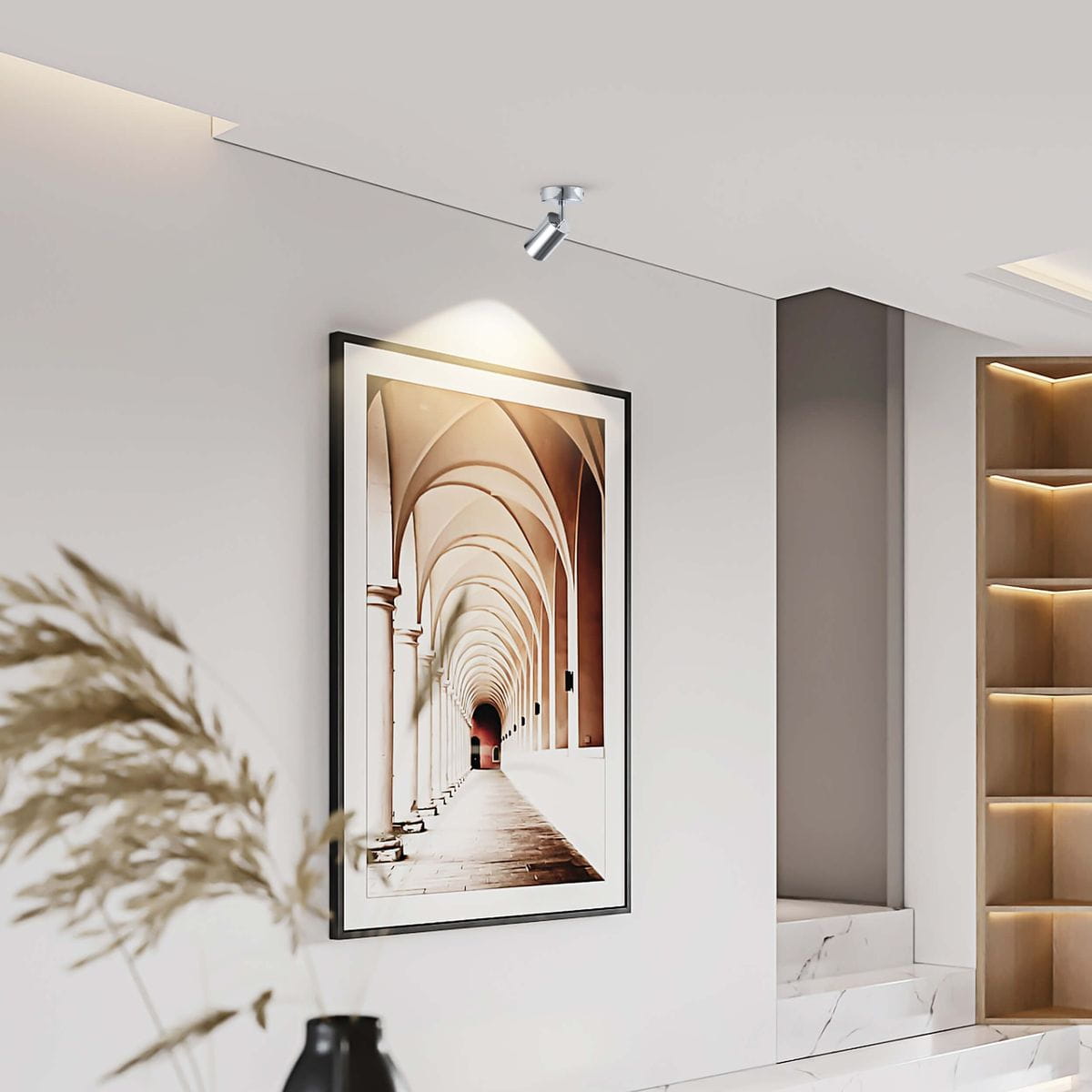 Lampa sufitowa Belize w chromie z jedną oprawą GU10, zamontowana na suficie, oświetlająca obraz w ramie. Prosta, nowoczesna konstrukcja, skierowana w dół, w minimalistycznym wnętrzu. Tło jasne, z elementami dekoracyjnymi.
