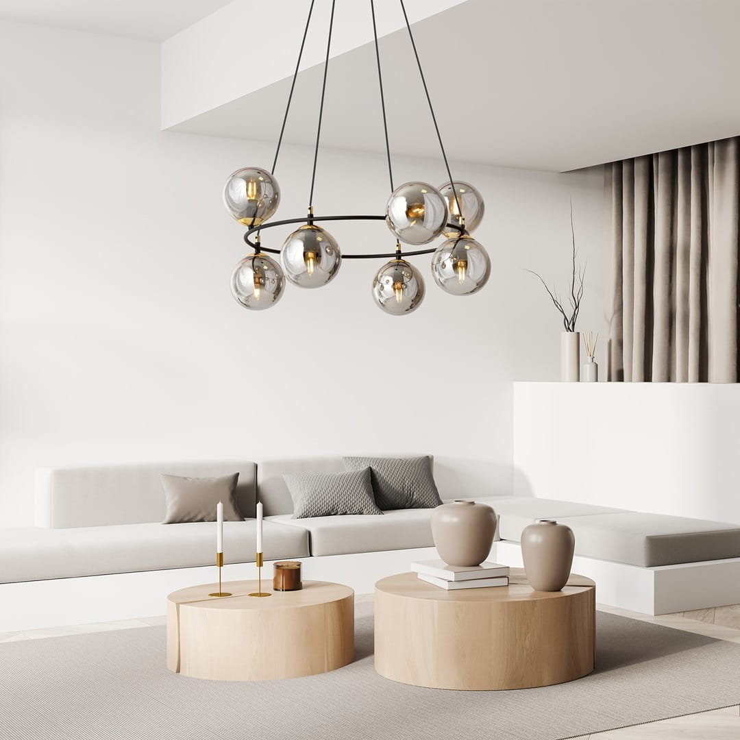 Lampa wisząca Azura z ośmioma kloszami E14 w czarnym i grafitowym kolorze, zawieszona nisko, we wnętrzu. Klosze mają przezroczyste, okrągłe formy, a podstawowe elementy są w kolorze złotym. Tło jasne, minimalistyczne z meblami w neutralnych barwach.