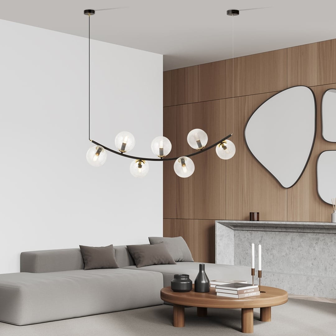 Lampa wisząca Ritz z siedmioma żarówkami E14 w czarnej i transparentnej obudowie. Zawieszona w stylu łukowym, na cienkich linkach, w nowoczesnym wnętrzu z drewnianymi akcentami i stonowanym meblem.
