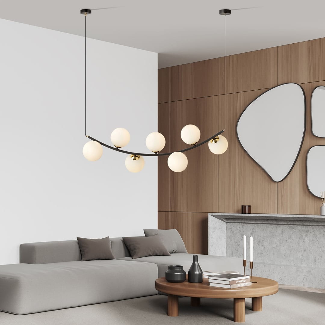 Lampa wisząca Ritz z siedmioma źródłami światła E14 w kolorze czarnym i białym. Ma nowoczesny, lekko zakrzywiony kształt, z opalowymi kloszami. Zawieszona na cienkich linkach w minimalistycznym wnętrzu z drewnianymi elementami.