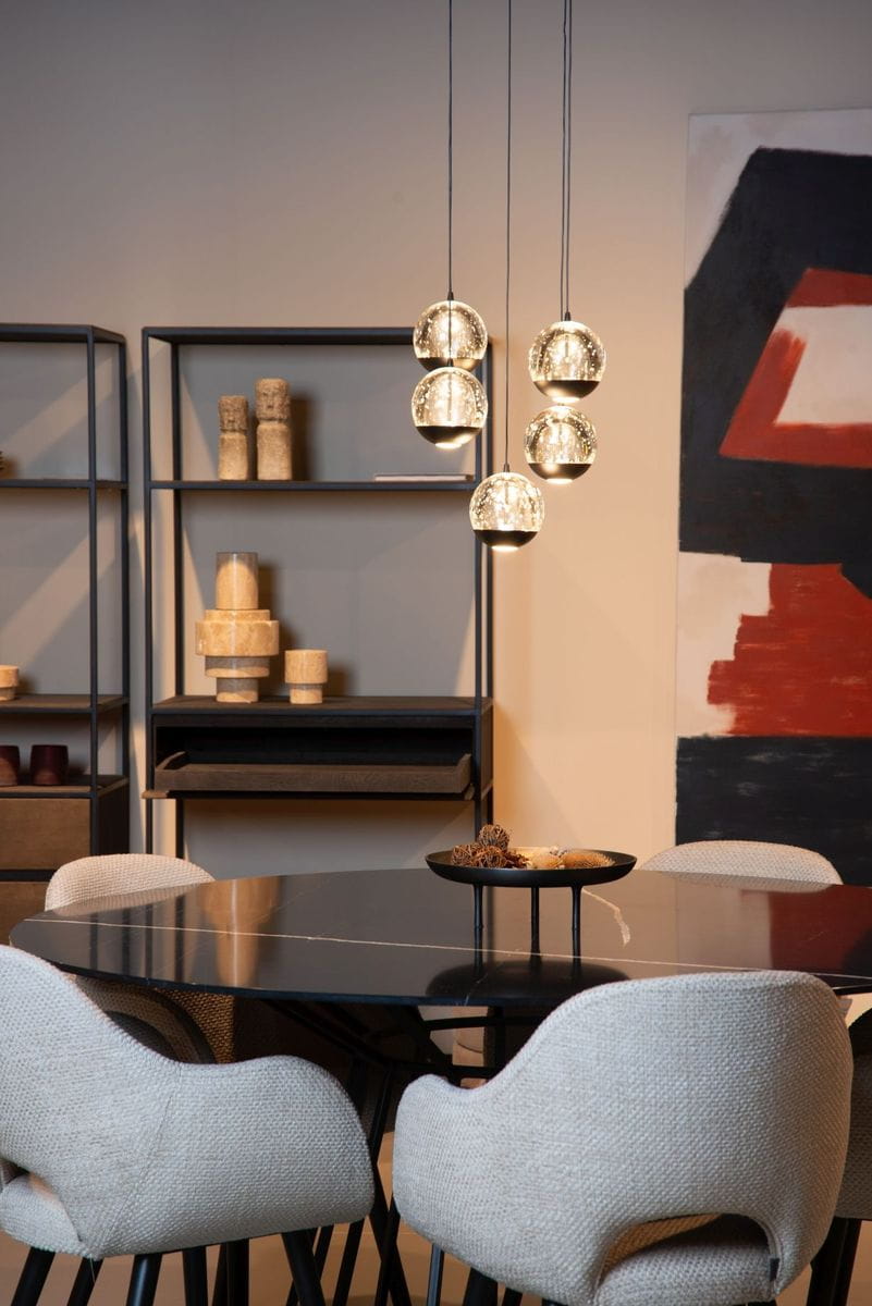 Lampa wisząca Sentubal z pięcioma kulistymi kloszami, czarna, z wbudowanym oświetleniem LED (5x5,2W). Zawieszona w poziomie nad okrągłym stołem, w tle minimalistyczna aranżacja z regałem i abstrakcyjnym obrazem.