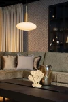 Lampa wisząca Signala 1xE27 w kolorze złotym i czarnym z okrągłym kloszem z opalowego szkła, zawieszona nad stolikiem w eleganckim wnętrzu z sofą i dekoracjami, w ujęciu frontalnym.