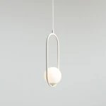Kremowa lampa wisząca Riva 1-punktowa z okrągłą, matową kulą oraz metalowym, owalnym uchwytem. Zawieszona na cienkim, białym przewodzie. Minimalistyczny design, idealna do nowoczesnych wnętrz.