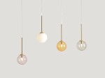 Lampa wisząca Bosso z czterema kulistymi kloszami w kolorze różowym, białym, żółtym i przezroczystym, zawieszona na złotych mocowaniach. Klosze mają różne odcienie i są umieszczone na cienkich, białych linkach, na szarym tle.