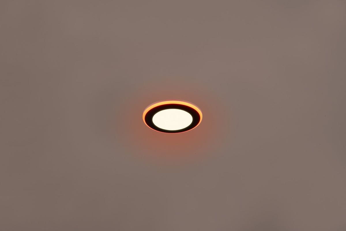 Oprawa do zabudowy Argus w kolorze czarnym, o okrągłym kształcie. Posiada dwa źródła LED (4W + 1W) oraz funkcję RGBW. Widoczna ciepła, pomarańczowa poświata wokół białego klosza, montowana w suficie.