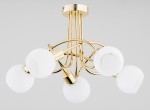 Lampa wisząca Eryka z pięcioma oprawami E14, złota. Konstrukcja z metalowych, błyszczących ramion, zakończona białymi, okrągłymi kloszami. Ujęcie z dołu, ukazujące detale wykończenia oraz kształt kloszy. Tło w jasnoszarym kolorze.