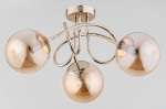 Lampa sufitowa Banko w kolorze antycznego złota z trzema kulistymi kloszami. Klosze mają delikatny, przezroczysty odcień, a metalowa konstrukcja jest złożona z finezyjnych linii. Produkt zamontowany na suficie, widok z dołu.