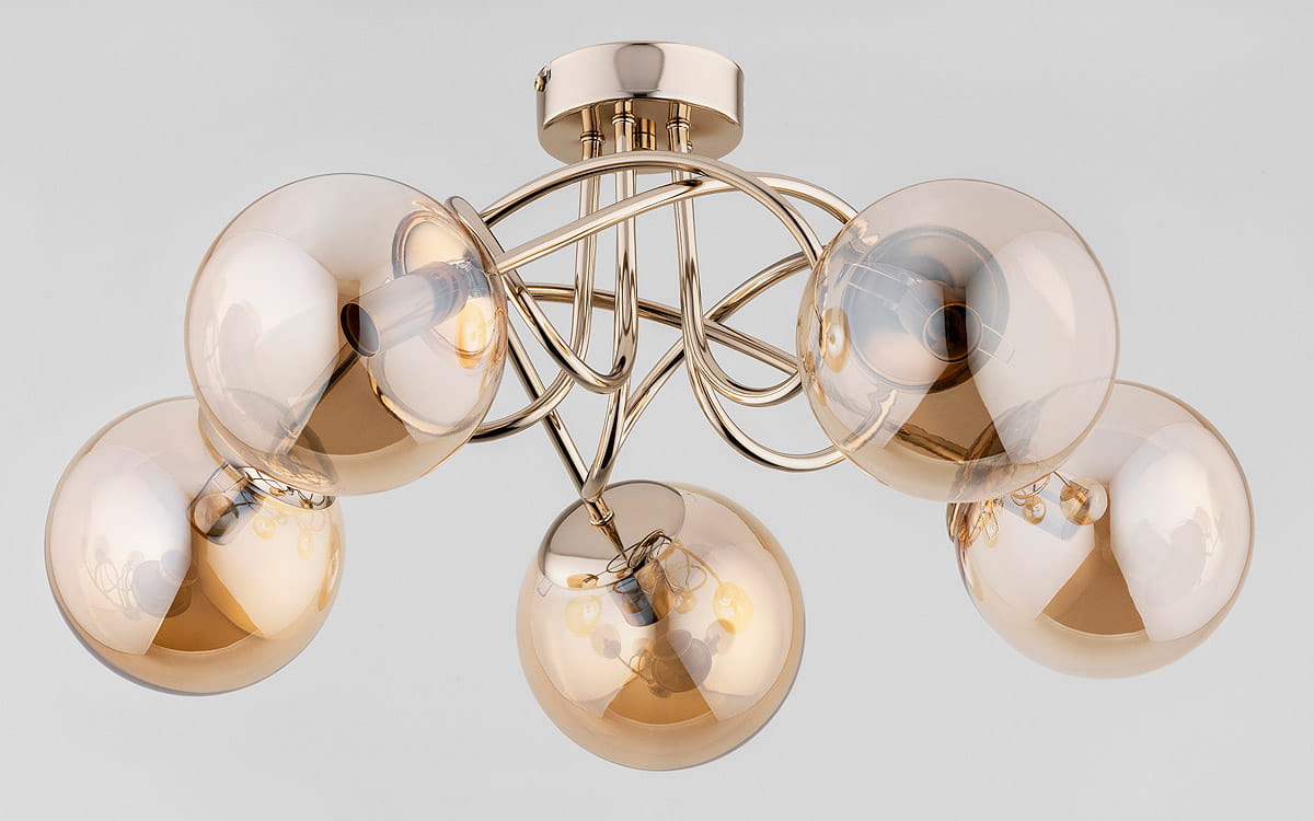 Lampa sufitowa Banko w kolorze antycznego złota z pięcioma szklanymi kloszami w odcieniu brązowym, z metalową konstrukcją. Ujęcie frontalne, złożona w kształcie wiru. Klosze mają zaokrąglony kształt, ukazując źródła światła wewnątrz.