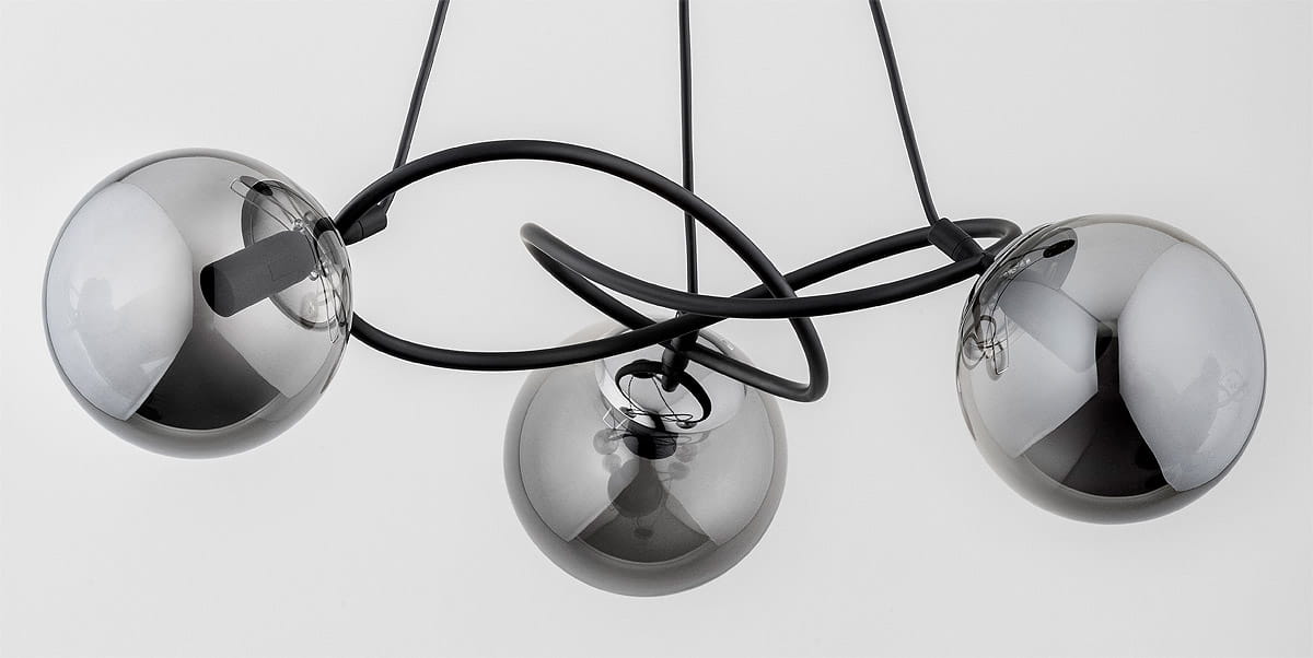 Lampa wisząca Velta z trzema kulami w kolorze czarnym i chromowanym. Kule mają błyszczące, półprzezroczyste wykończenie, a całość zawieszona jest na czarnych przewodach. Ujęcie z góry, ukazujące unikalny kształt i rozmieszczenie elementów.