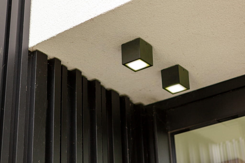 Ciemnoszara lampa sufitowa elewacyjna Gemini z jedną diodą LED o mocy 7W i temperaturze barwowej 4000K. Ujęcie z dołu, zamontowana pod sufitem, kwadratowy kształt z białym panelem świetlnym na górze.