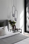 Lampa wisząca Davos 1xE14 w kolorze czarnym i grafitowym, o minimalistycznym kształcie, zawieszona w sypialni nad stolikiem nocnym. W tle widoczna dekoracyjna roślina oraz poduszki na łóżku, na jasnym tle.