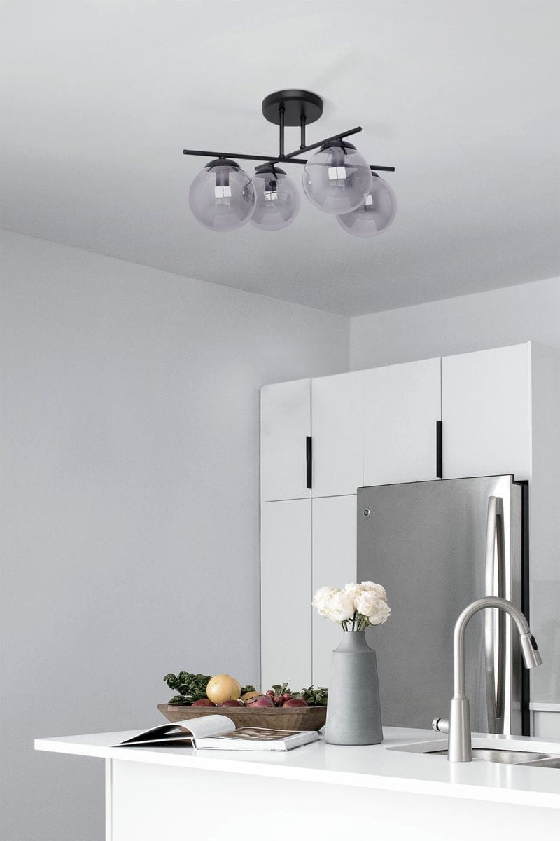 Lampa sufitowa Gamma w kolorze czarnym i grafitowym z czterema kloszami E14, zawieszona na prostym, metalowym stelażu. Klosze w odcieniu szaro-przezroczystym, umieszczone na poziomej belce, w nowoczesnej kuchni z białymi meblami.