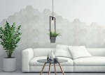 Czarna lampa wisząca Estera z funkcją kwietnika, zawieszona na cienkim przewodzie. W dolnej części znajduje się doniczka z zieloną rośliną. Lampa umieszczona w nowoczesnym wnętrzu z hexagonalną ścianą i białą sofą.
