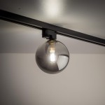 Lampa Tracer na szynę z jedną oprawą G9, w kolorze czarnym i grafitowym. Szklana kula z ciemnym szkłem, zawieszona na metalowej podstawie. Oświetlenie skierowane w dół, zamontowane na górnej krawędzi.