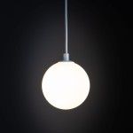 Lampa wisząca Tracer 1xG9 w kolorze białym, z okrągłym, matowym kloszem. Ujęcie z dołu, zawieszona na białym kablu. Tło ciemne, podkreślające prosty design. Idealna do nowoczesnych wnętrz.