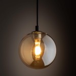 Lampa wisząca Tracer z jedną oprawą G9, w kolorze czarnym z bursztynowym kloszem. Okrągły, przezroczysty klosz z widoczną żarówką, zawieszony na czarnym przewodzie. Ujęcie z bliska, podkreślające detal i fakturę szkła.