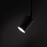 Reflektor spot Tracer 1xGU10 w kolorze czarnym, o cylindrycznym kształcie, umieszczony na ruchomej głowicy. Źródło światła skierowane w dół, z gładką matową powierzchnią. Tło ciemne, podkreślające minimalistyczny design.