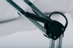 Lampka biurkowa Cosmo z chromowanym ramieniem, widok z boku. Widać metalowy mechanizm ruchomy oraz sprężynę dla regulacji wysokości. Tło proste, białe, podkreślające detale konstrukcji.