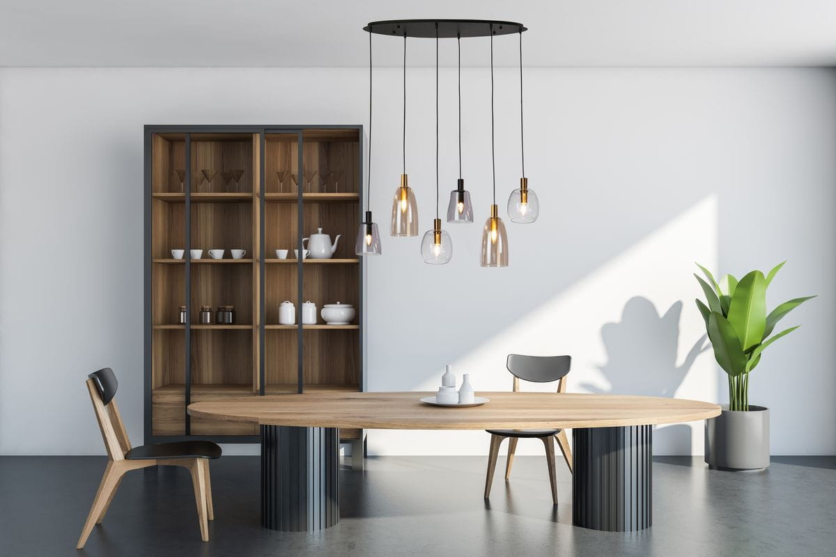 Lampa wisząca Divine 6xE14 w kolorze czarnym i multikolorowym, z sześcioma szklanymi kloszami, zawieszona na okrągłej podstawie. Elementy złote i czarne, wiszące na cienkich kablach, w nowoczesnej aranżacji nad stołem w jadalni.