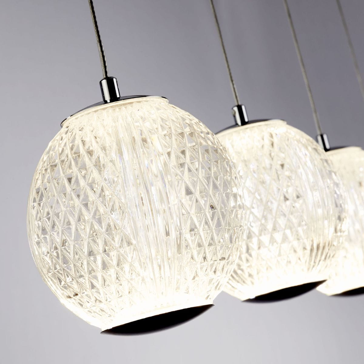 Lampa wisząca Allure z pięcioma kloszami LED o mocy 28W, w chromowanej oprawie. Klosze mają przezroczystą, teksturowaną powierzchnię w kształcie kul, zawieszone na cienkich linkach, na szarym tle.
