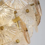 Lampa wisząca Wagon Wheel 5xG9 w kolorze brązowym i bursztynowym z przeźroczystymi kloszami. Szklane, okrągłe elementy z wyraźnym wzorem, zawieszone na złotej konstrukcji, prezentują elegancki design.