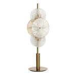 Lampa stołowa Wagon Wheel w kolorze brązowym i bursztynowym, z przezroczystymi kloszami w kształcie kół. Ustawiona pionowo na okrągłej podstawie, z trzema kloszami o teksturowanej powierzchni, podświetlającymi wnętrze.