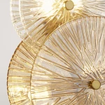 Brązowa lampa stołowa Wagon Wheel z sześcioma kloszami G9, wykonana z przezroczystego szkła z fakturą przypominającą koło. Klosze emitują ciepłe światło bursztynowe, z centralnym mocowaniem w kolorze złotym, w ujęciu z góry.