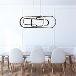 Czarna lampa wisząca Clip z trzema diodami LED, o nowoczesnym kształcie złożonym z dwóch przeplatających się owalnych elementów. Zawieszona nad drewnianym stołem w jasnym wnętrzu z okrągłymi, tapicerowanymi krzesłami.