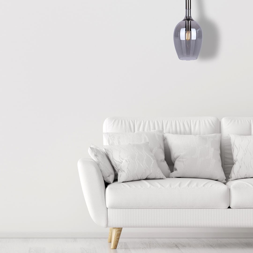 Lugano lampa wisząca 1xE14 w kolorze chromu, o zaokrąglonym kształcie, zawieszona na cienkich linkach. Lampa znajduje się nad białą sofą z poduszkami w jasnych odcieniach, na tle jasnej ściany.