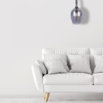 Lugano lampa wisząca 1xE14 w kolorze chromu, o zaokrąglonym kształcie, zawieszona na cienkich linkach. Lampa znajduje się nad białą sofą z poduszkami w jasnych odcieniach, na tle jasnej ściany.