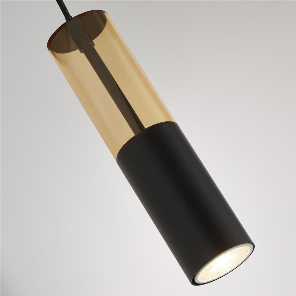 Lampa wisząca Merrygold 1xGU10 w kolorze czarnym z bursztynowym kloszem. Okrągła podstawa z matowego metalu i przezroczysty klosz, zawieszona na cienkim przewodzie. Zbliżenie na detale struktury i kształtu lampy.