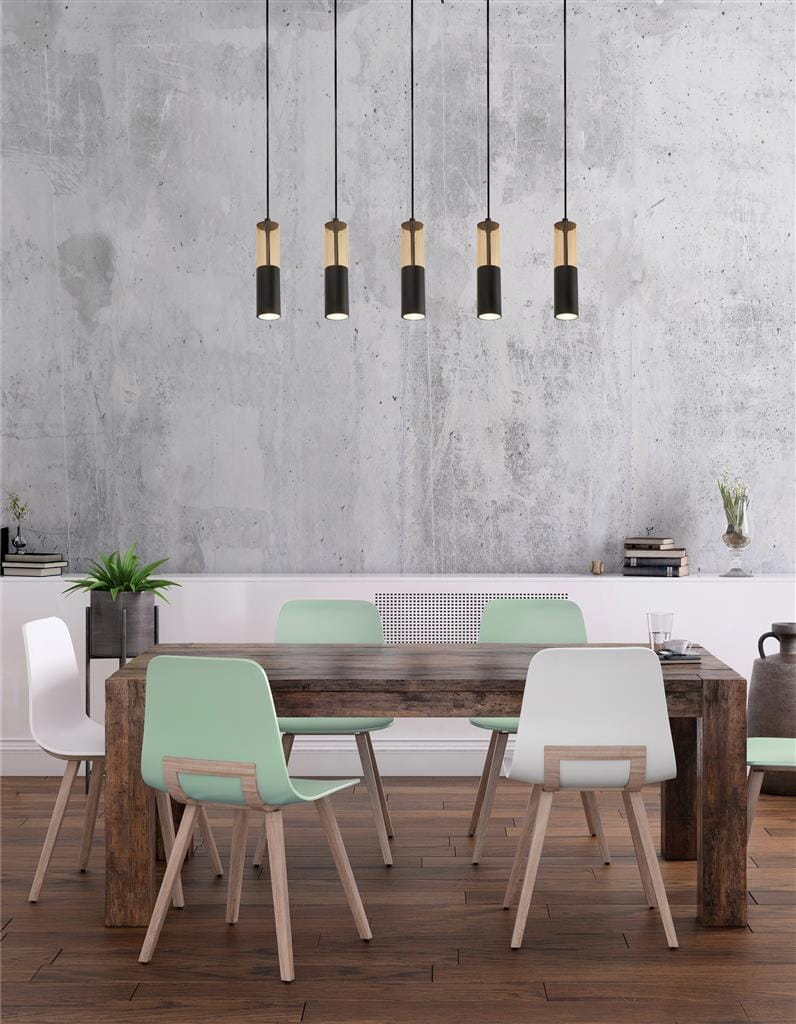 Lampa wisząca Merrygold 5xGU10 w kolorze czarnym z bursztynowymi akcentami, zawieszona nad drewnianym stołem w jadalni. Lampa składa się z pięciu cylindrycznych kloszy, umieszczonych na długich czarnych przewodach. Tło w odcieniach szarości.