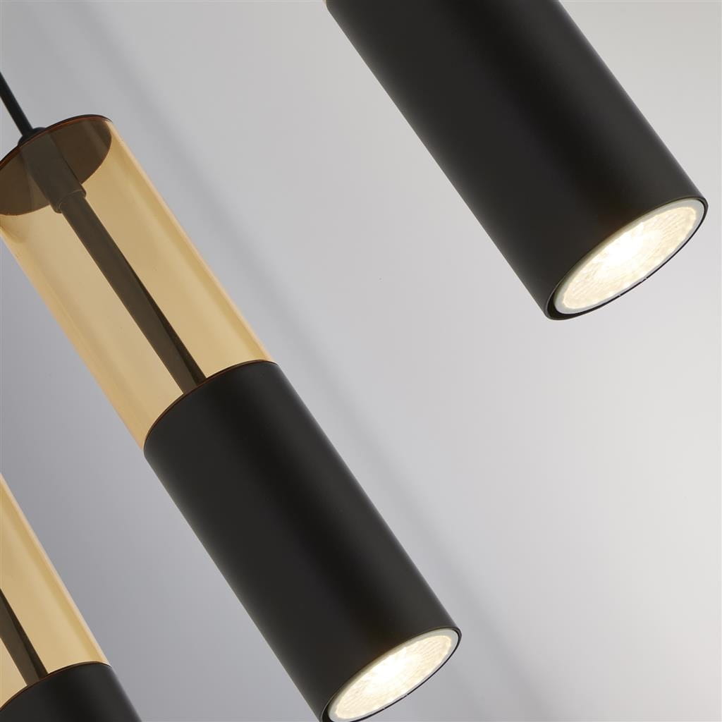 Lampa wisząca Merrygold z pięcioma oprawami GU10, w kolorze czarnym z bursztynowymi kloszami. Widoczny detal: cylindryczne klosze z transparentnego szkła i matowe wykończenie. Produkt zawieszony, w zbliżeniu na detale kloszy i źródeł światła.