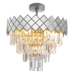 Lampa sufitowa Carisma w kolorze chromu z 9 gniazdami E14. Ozdobiona lustrzanym kloszem w diamentowy wzór oraz wiszącymi kryształowymi elementami, które odbijają światło, tworząc efektowną iluminację. Ujęcie z boku, pokazujące detale i fakturę.