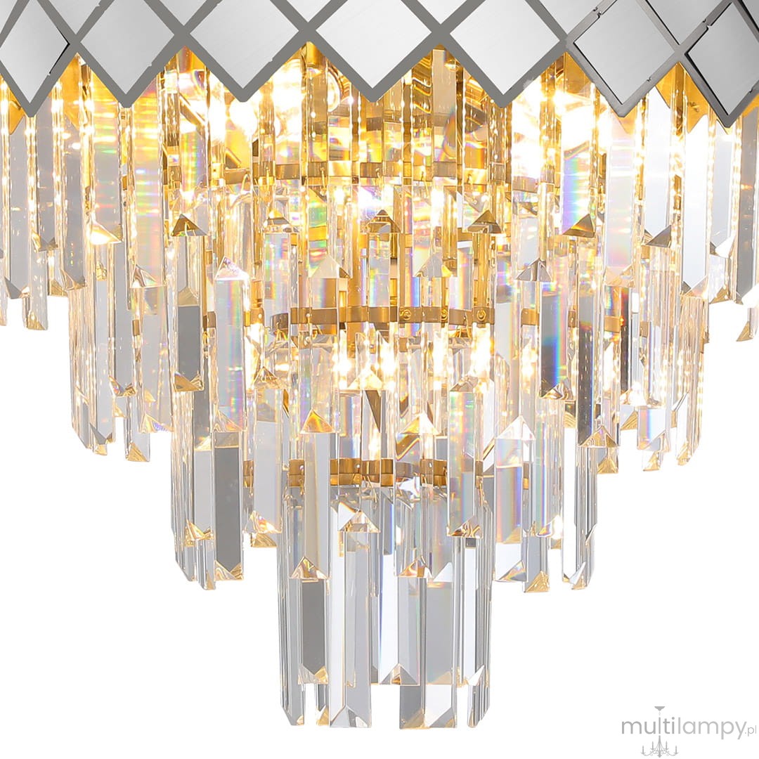 Lampa sufitowa Carisma 9xE14 w kolorze chromu, z dekoracyjnymi kryształowymi elementami. Widać lśniące, przezroczyste wiszące kryształy oraz geometryczny, lustrzany wzór na górnej części. Produkt umieszczony w pozycji wiszącej.