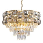 Lampa wisząca Luxuria 9xE14 w kolorze złotym, z dekoracyjnymi kryształkami w kształcie prostokątów i kropli, zawieszona na łańcuchu. Elegancki design, idealna do nowoczesnych wnętrz. Wymiary i detale mogą się różnić.