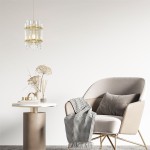 Lampa wisząca Alexandria 1xE14 w złotym kolorze, z przezroczystymi, prostokątnymi szklanymi elementami. Zawieszona nad okrągłym, białym stołem, w tle widoczny komfortowy fotel i dekoracyjne akcesoria.