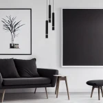 Czarna lampa wisząca Joker 3-punktowa, składająca się z trzech cylindrycznych kloszy z metalowymi elementami, wisząca nad szaro-czarną sofą, w minimalistycznym wnętrzu z białymi ścianami i dużymi obrazami.