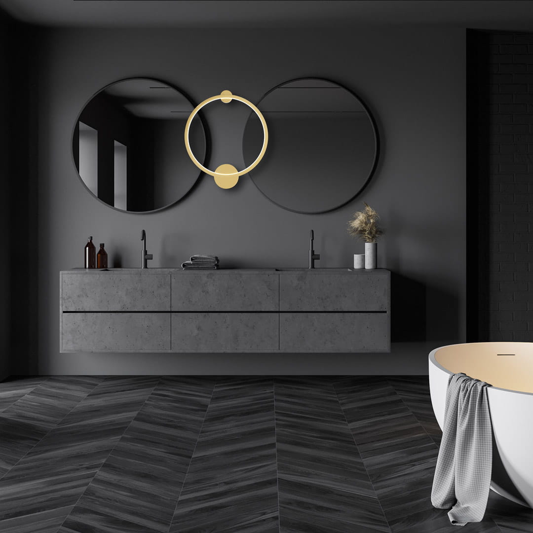 Złota lampa sufitowa Saturno D50 z jedną żarówką LED o mocy 25W, umieszczona w nowoczesnej łazience. Lampa ma okrągły kształt, z charakterystycznym elementem w centralnej części, na tle szarej ściany i dwóch okrągłych luster.