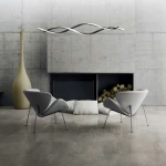 Lampa wisząca Grant w kolorze czarnym, z dwoma źródłami LED o mocy 38W, z unikalnym falistym kształtem. Zawieszona nad nowoczesnymi szarymi fotelami w minimalistycznym wnętrzu z betonowymi ścianami.