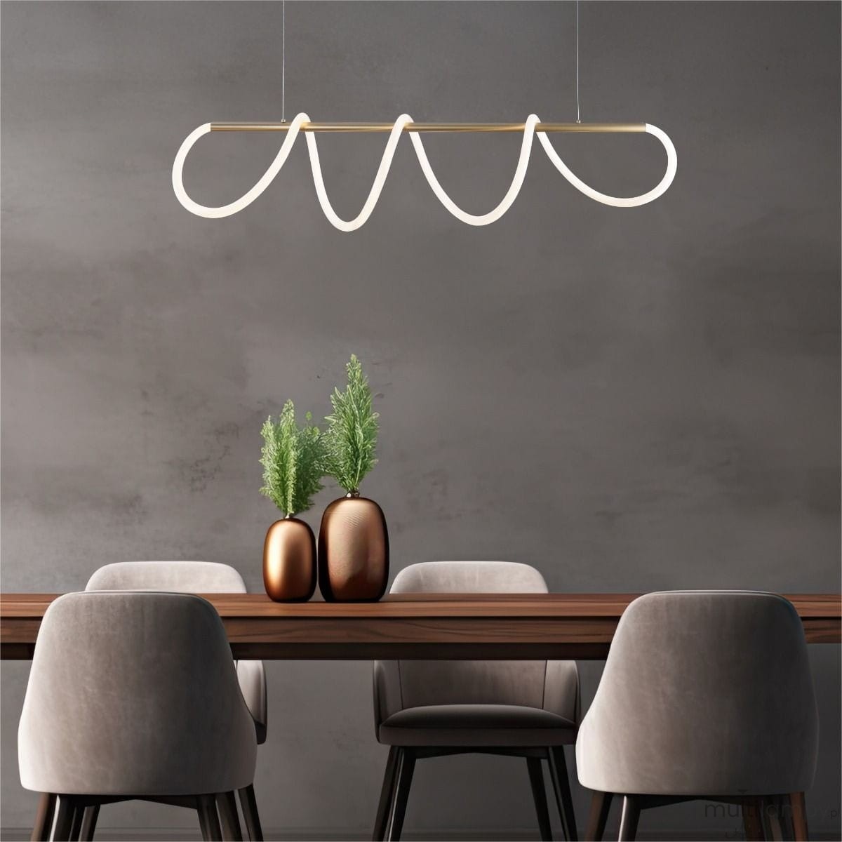 Lampa wisząca Balbo w kolorze złotym z elementami LED, o nowoczesnym, falistym kształcie. Zawieszona nad stołem, w tle widać drewniany stół oraz dekoracyjne wazony z roślinami. Ujęcie frontalne, na jednolitym, ciemnym tle.