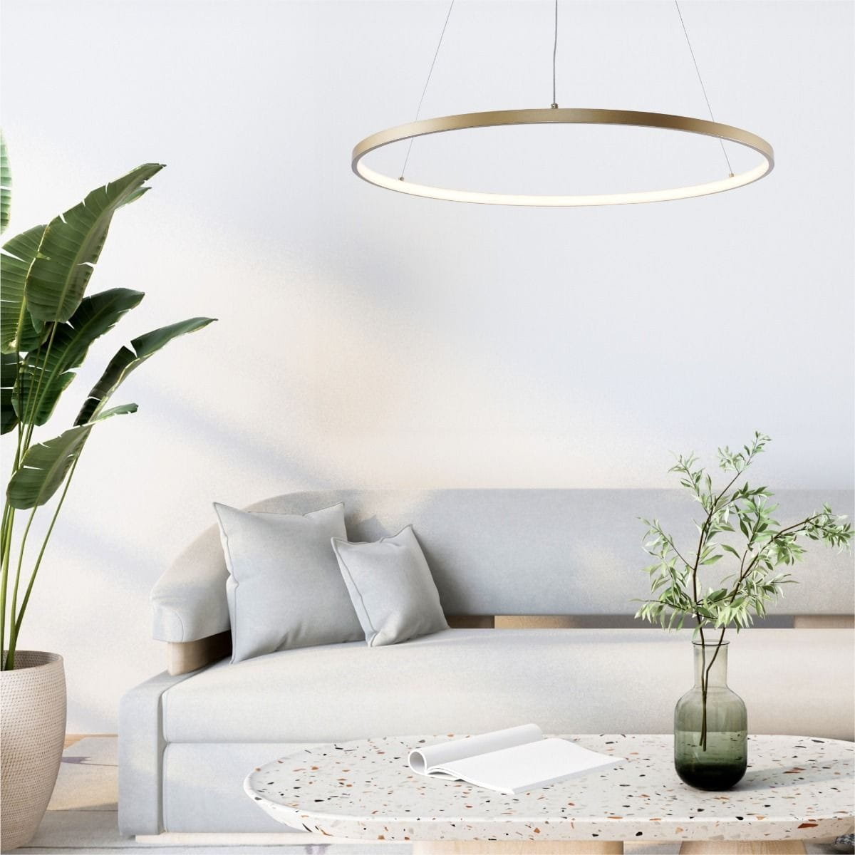 Lampa wisząca Breno D80 w kolorze złotym, o okrągłym kształcie, zawieszona nad kanapą. Wyposażona w 1 żarówkę LED o mocy 36W, emitująca miękkie światło. W tle widoczna roślina oraz stół z okrągłym blatem.
