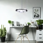 Lampa wisząca Orbit 3xE27 w kolorze czarnym i białym, z okrągłym kloszem, zawieszona nad biurkiem. W tle widoczna roślina, biurko z książkami i akcesoriami oraz jasna ściana.