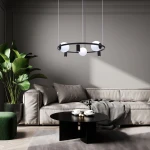 Lampa wisząca Orbit w kolorze czarnym i białym, z trzema oprawami E27 i trzema GU10, zawieszona w salonie nad okrągłym stołem.