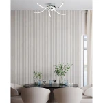Lampa sufitowa Focus 5xLED/35W w chromowanej obudowie, z ozdobnymi, falistymi ramionami. Zainstalowana na suficie, w nowoczesnym wnętrzu, nad okrągłym stołem z krzesłami w kolorze beżowym. Tło w jasnych, pionowych pasach.