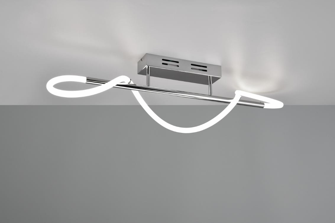 LED lampa sufitowa Argos w kolorze chromu, z jedną oprawą. Posiada nowoczesny, falisty kształt świetlówki w białym kolorze. Zamontowana na prostokątnej podstawie przy suficie, w ujęciu frontalnym. Tło w odcieniu szaro-beżowym.