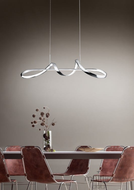 Lampa wisząca Perugia LED w kolorze chromu, umieszczona nad stołem. Posiada nowoczesny, falisty kształt. W tle widoczna drewniana stół oraz krzesła w odcieniach brązu, na ścianie jednolite tło w jasnym kolorze.