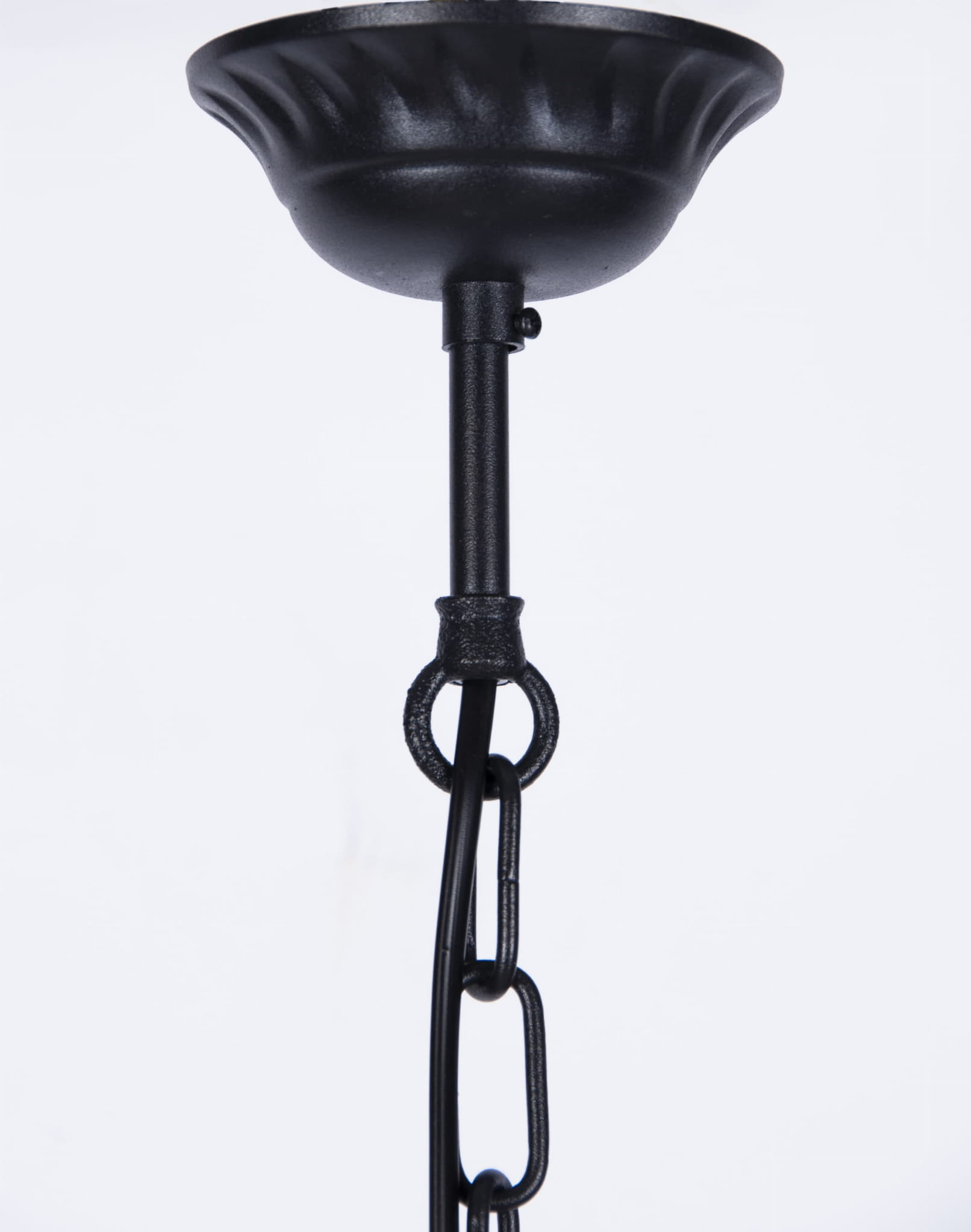 Wisząca lampa ogrodowa Lozana w kolorze czarnym, z metalowym kloszem o falistym kształcie, zawieszona na łańcuchu. Ujęcie z dołu, ukazujące szczegóły mocowania i teksturę materiału. Idealna do oświetlenia przestrzeni zewnętrznych.