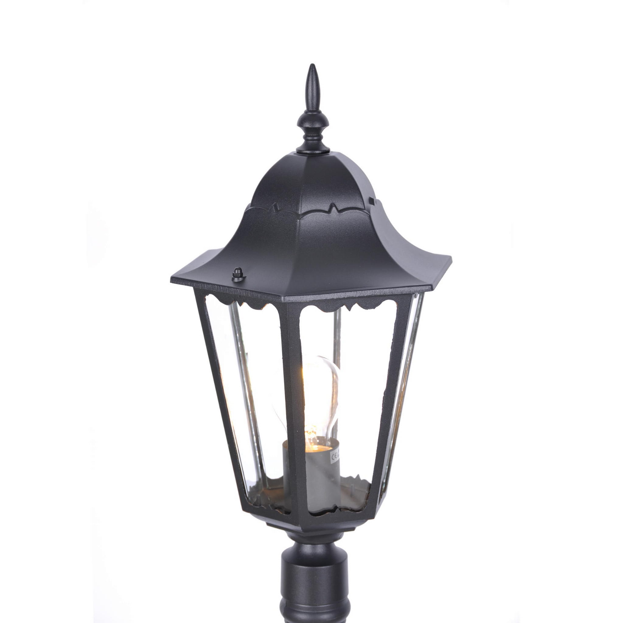 Czarna lampa ogrodowa Lozana H114 z dekoracyjnym, sześciokątnym kloszem i metalową podstawą. Widoczny żarówka wewnątrz, przeszklone ścianki oraz ozdobny szczyt. Ujęcie zbliżeniowe na górną część lampy.