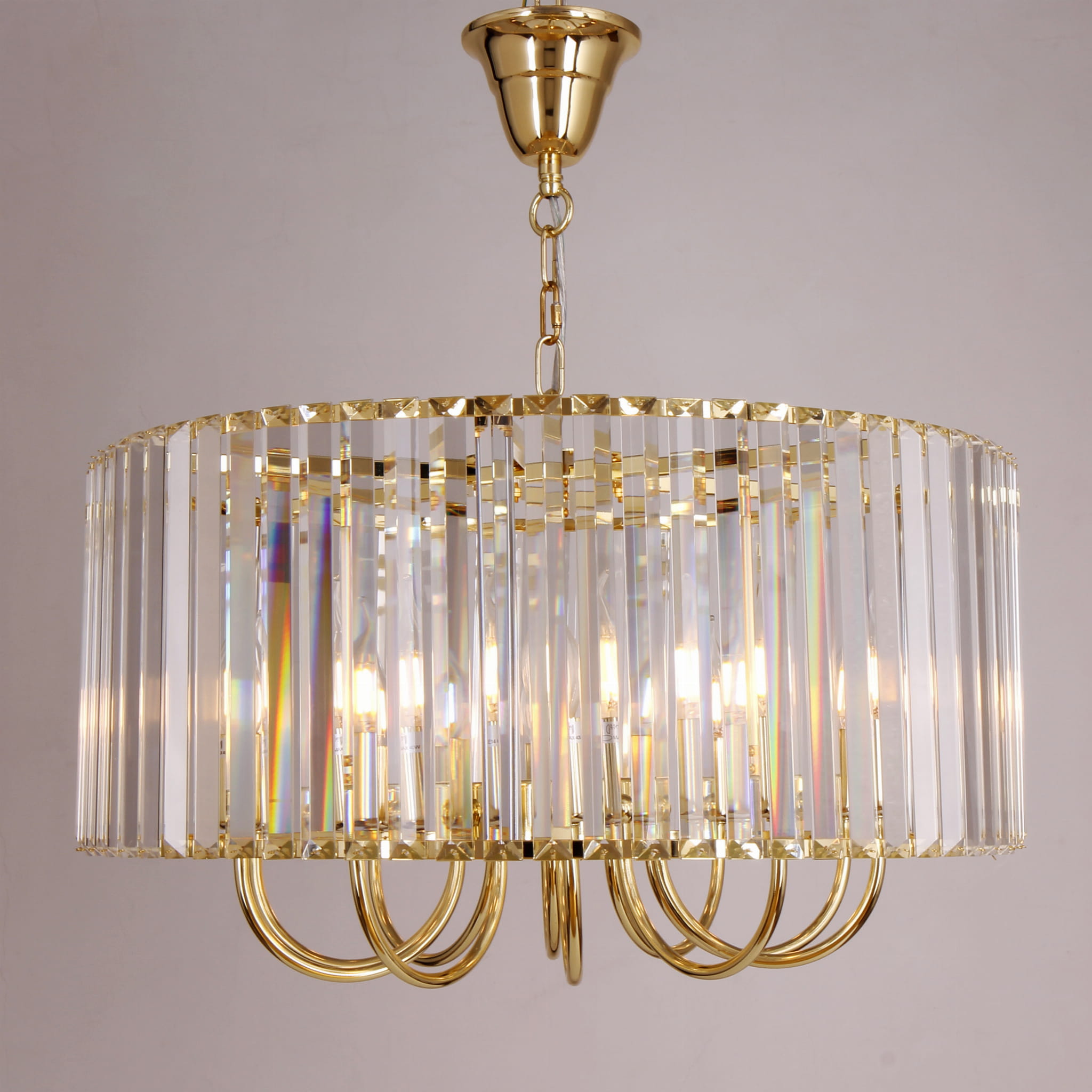 Lampa wisząca Paris 10xE14 w kolorze złotym, z przezroczystymi akrylowymi żłobieniami. Okrągła, zawieszona na łańcuchu, z widocznymi źródłami światła wewnątrz. Elementy metalowe w błyszczącym złotym wykończeniu, elegancki design.